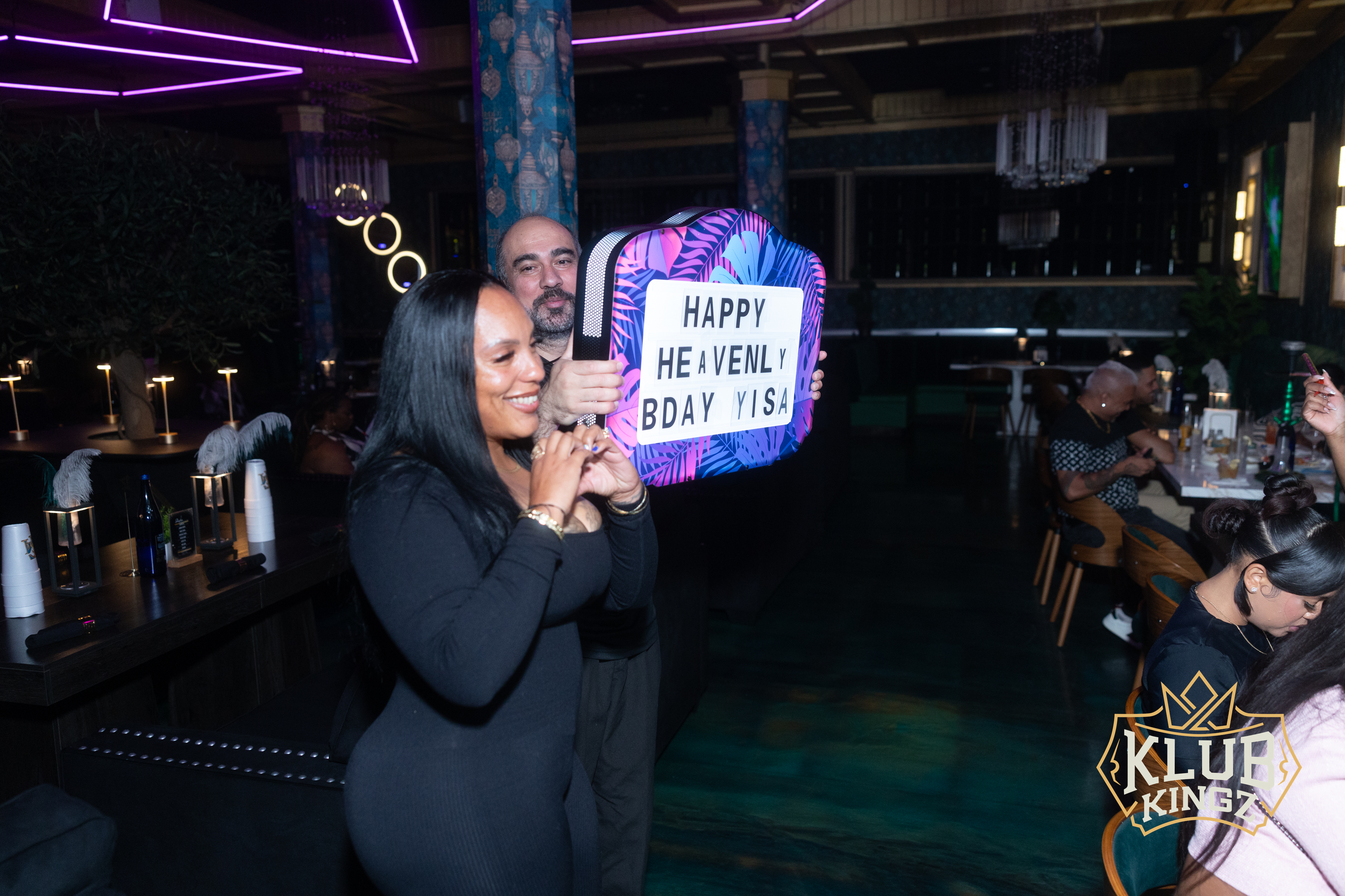 Couple celebrating a birthday with a "Happy Birthday" sign at Klub Kingz nightclub