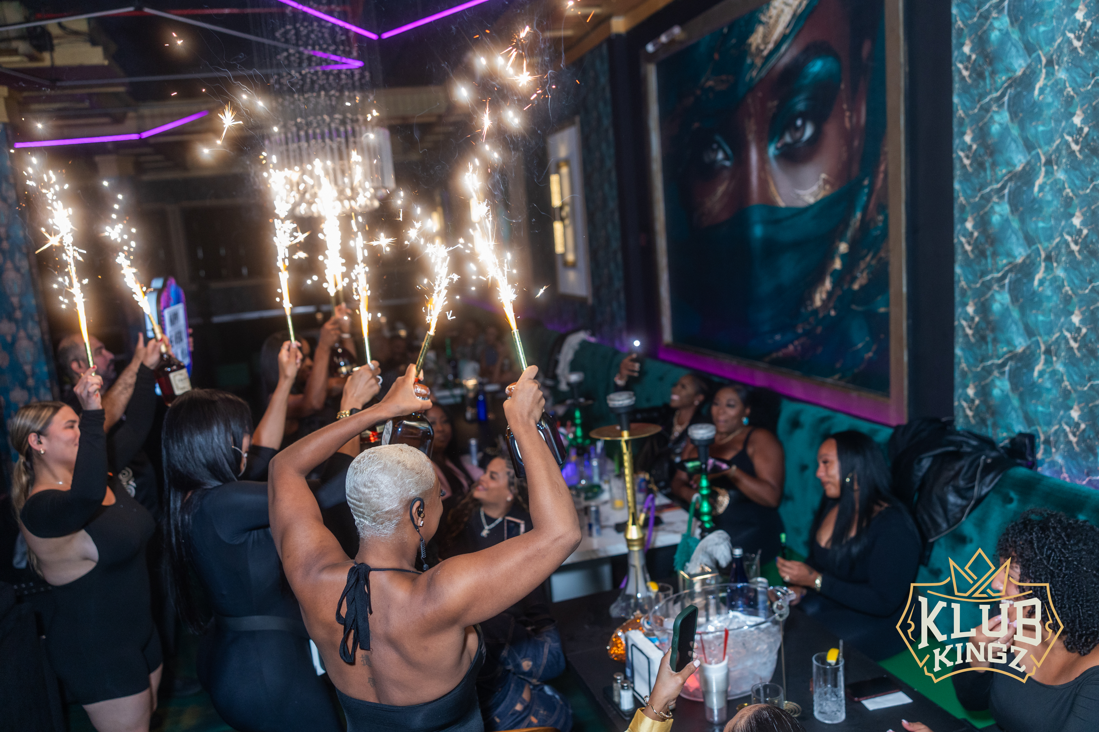 Guests raise sparkler bottle service at Klub Kingz nightclub, celebrating with hookah and cocktails.