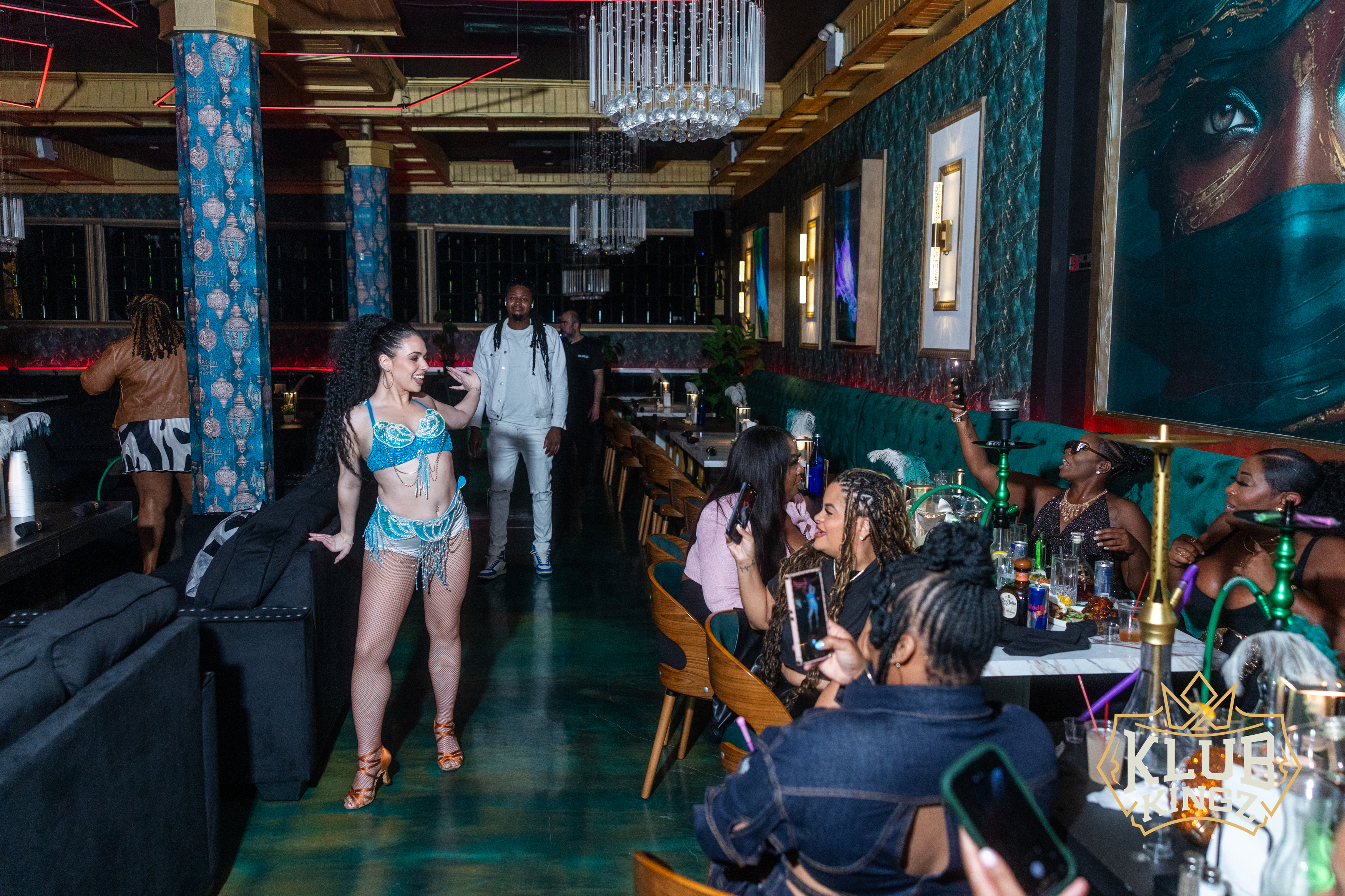 Costumed dancer performing for guests with hookahs and drinks at Klub Kingz nightclub lounge
