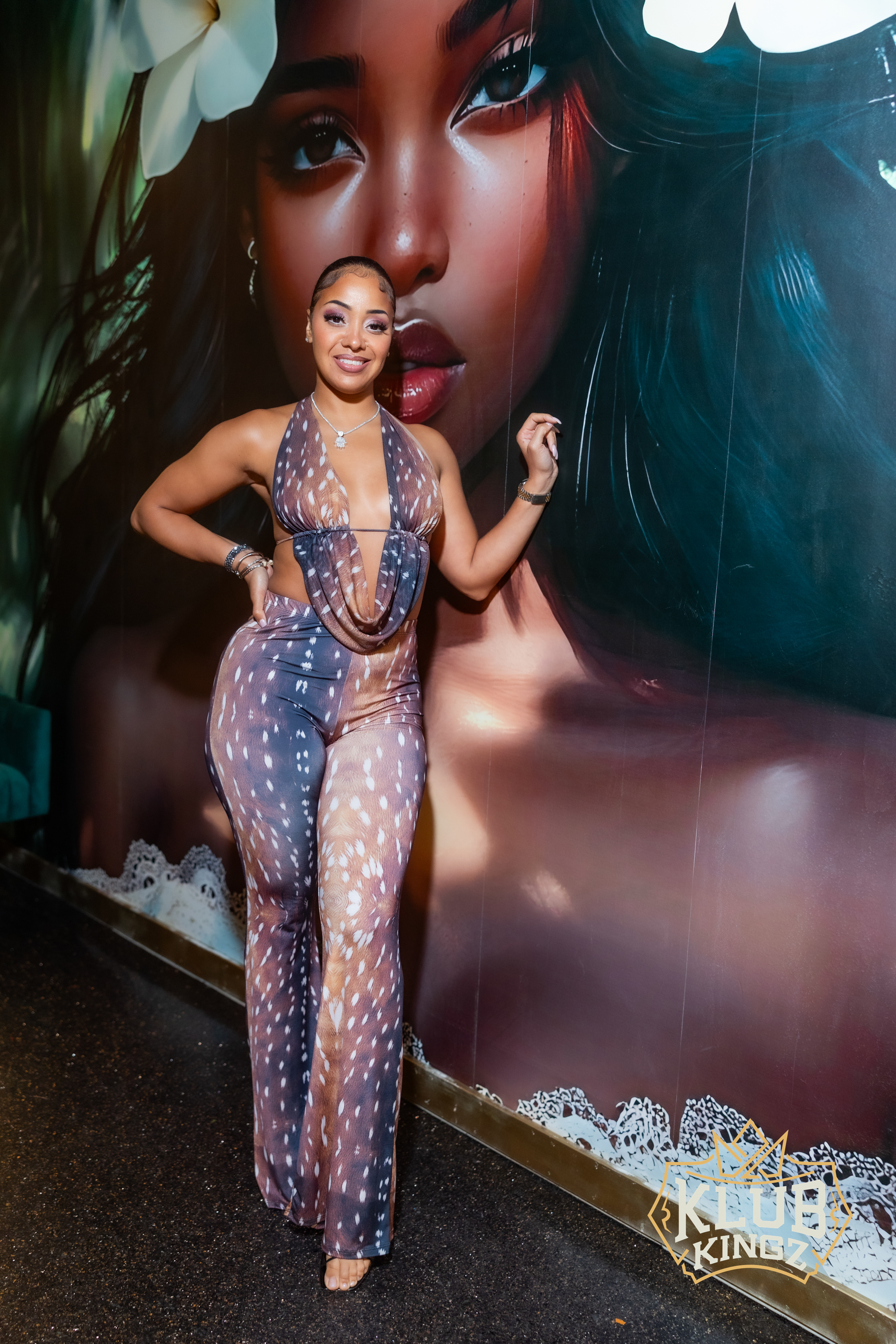 Guest posing in a patterned cutout jumpsuit by a mural wall at Klub Kingz nightclub