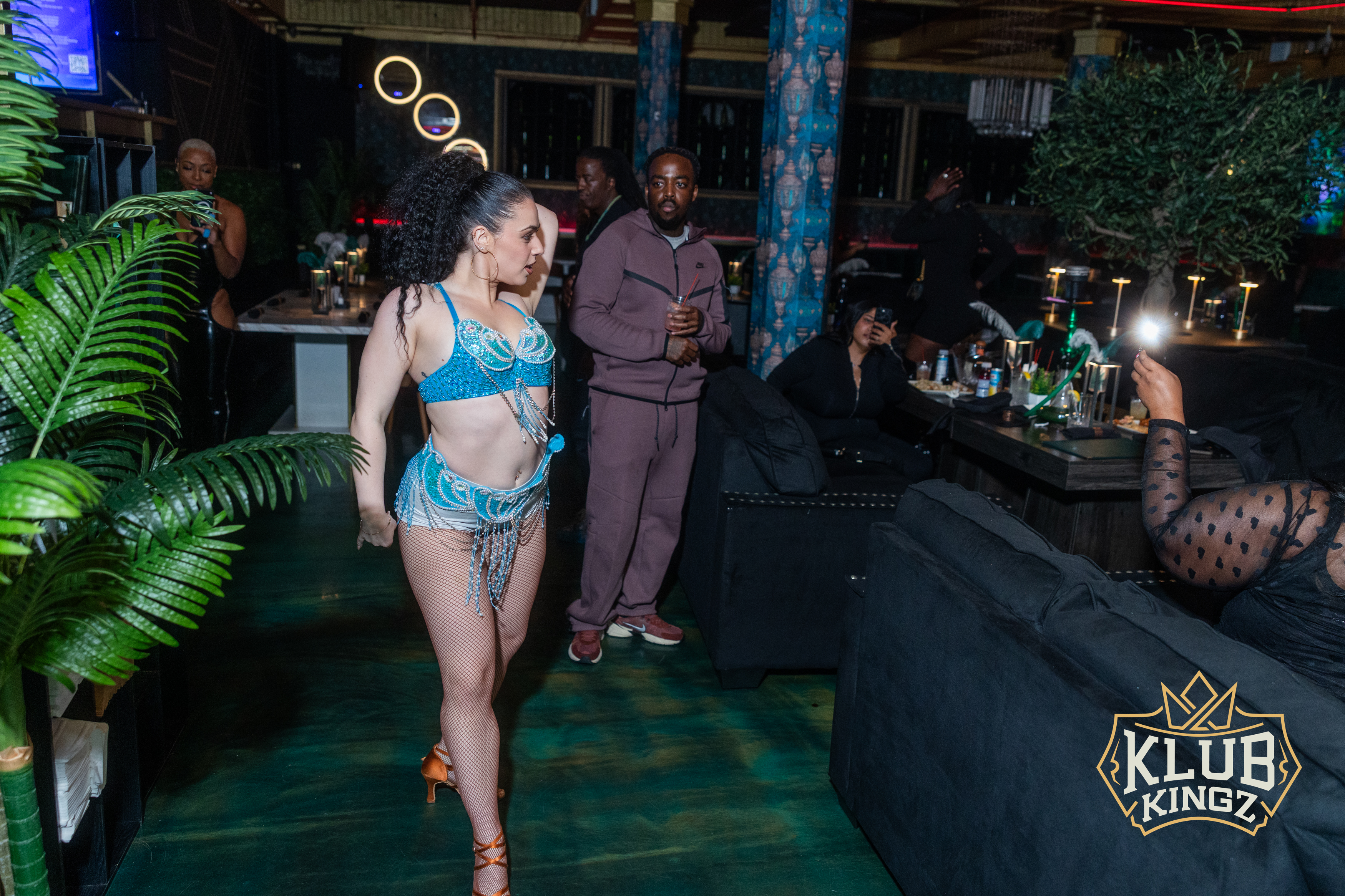 Performer in a sparkling blue costume walks through the crowd at Klub Kingz nightclub event