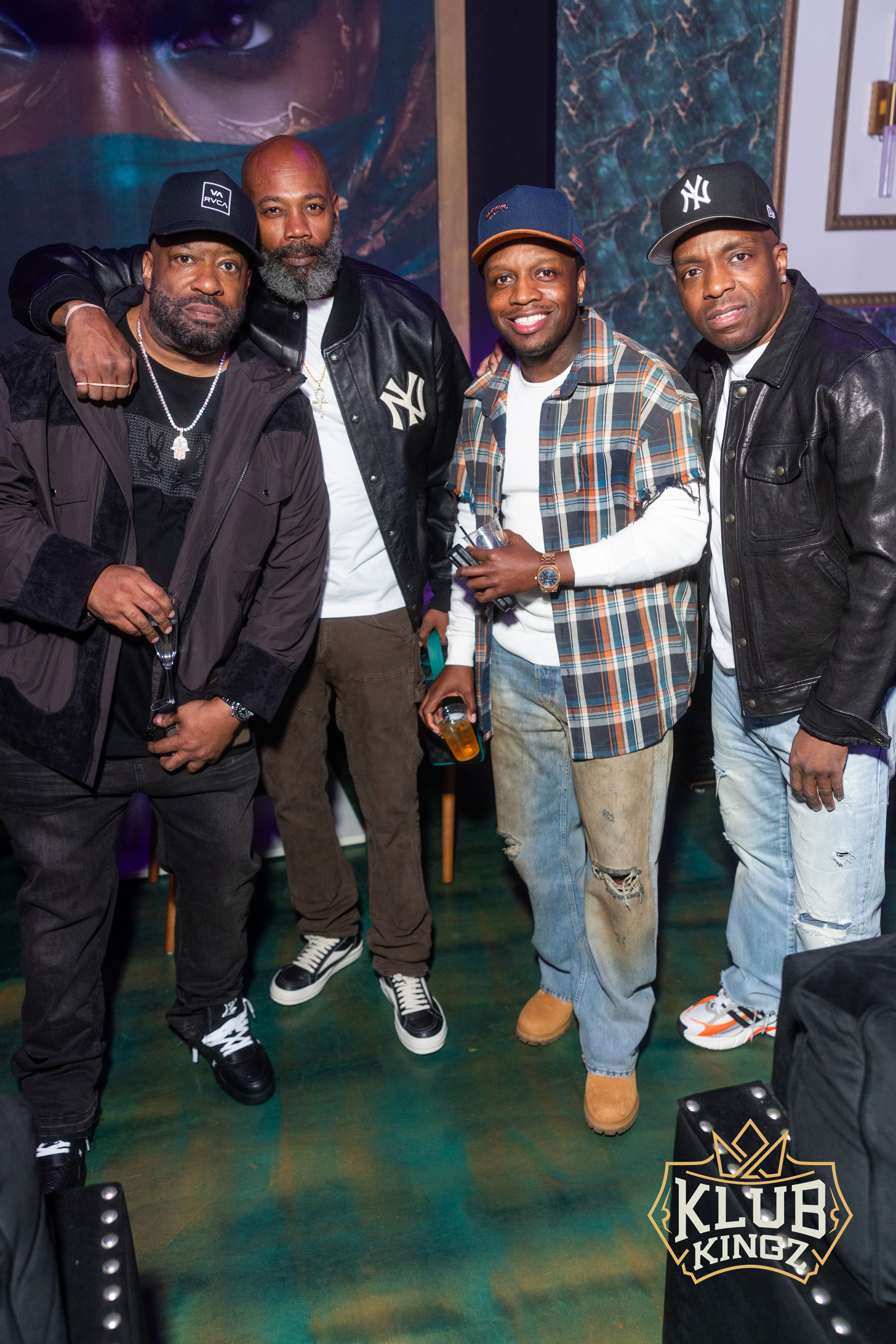 Four stylish friends posing together at a Klub Kingz nightlife event, wearing caps and jackets.