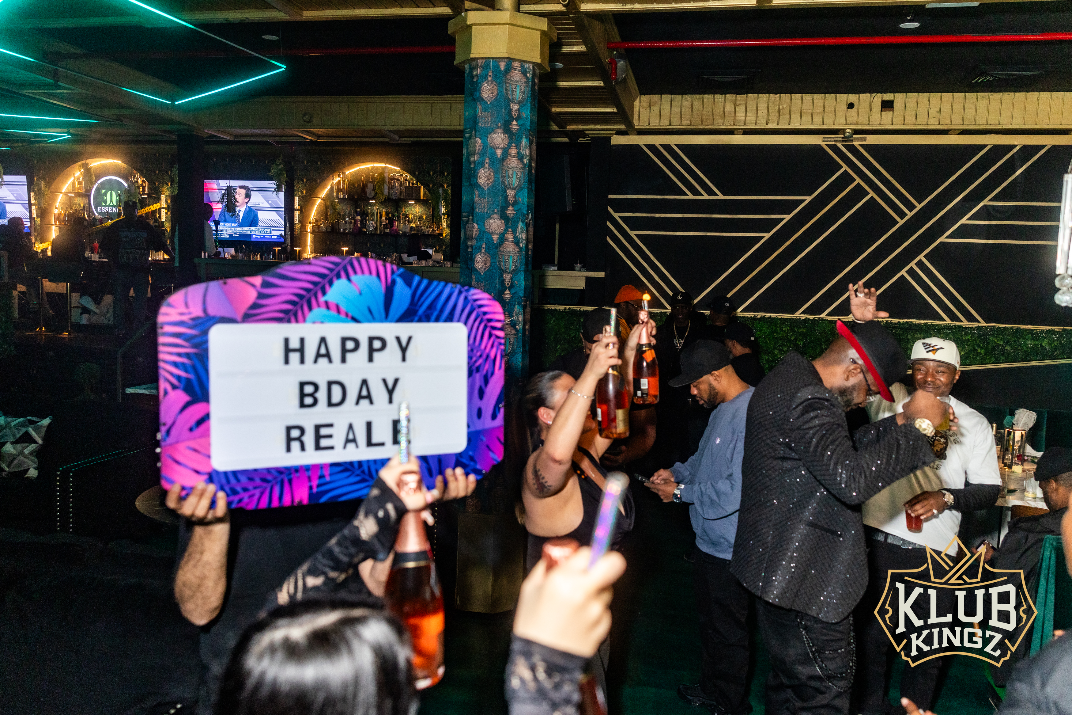 Guests celebrate a birthday with a lit-up sign and champagne bottles at Klub Kingz nightclub