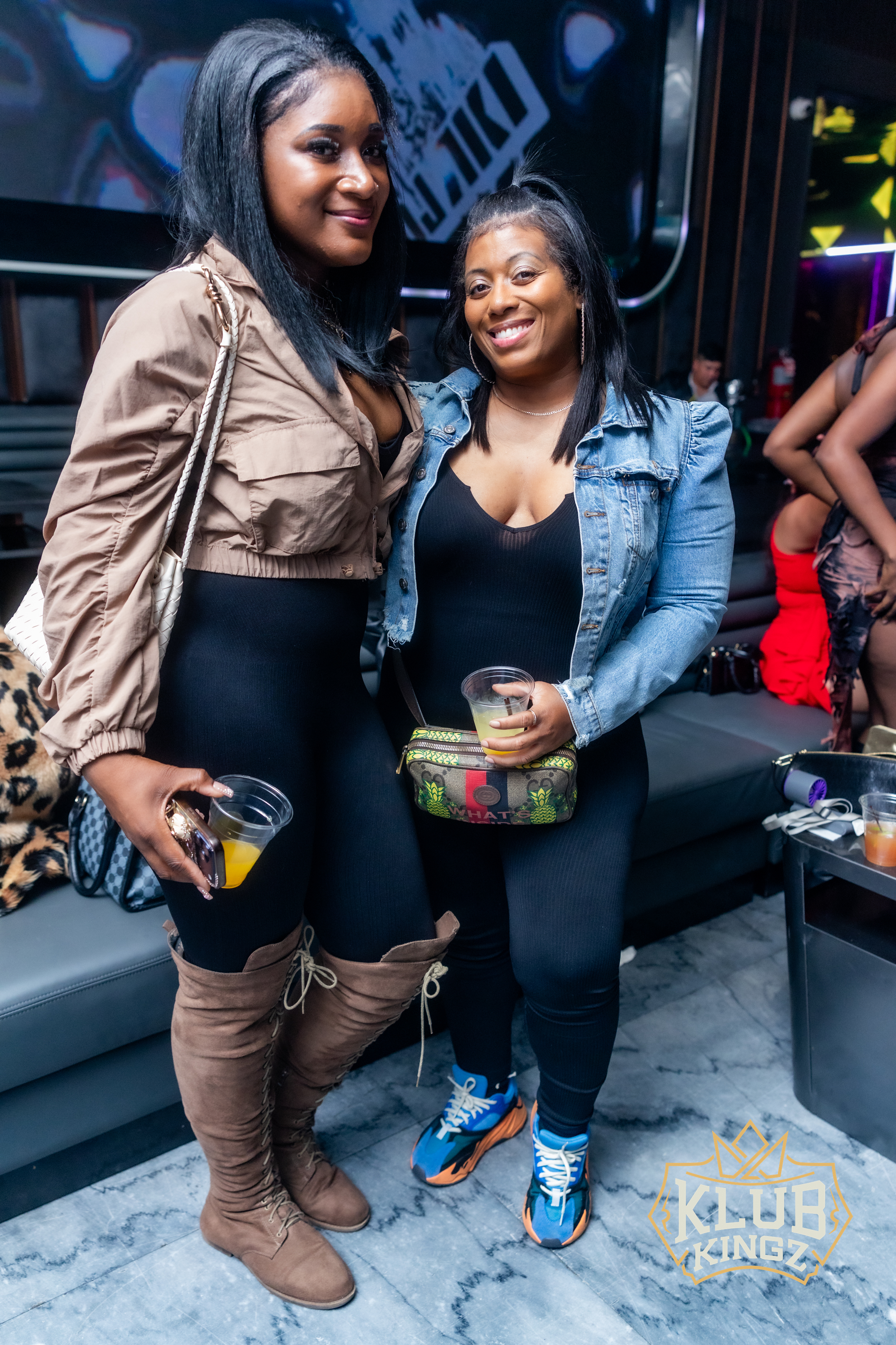 Two stylish women posing with drinks at Klub Kingz nightclub event