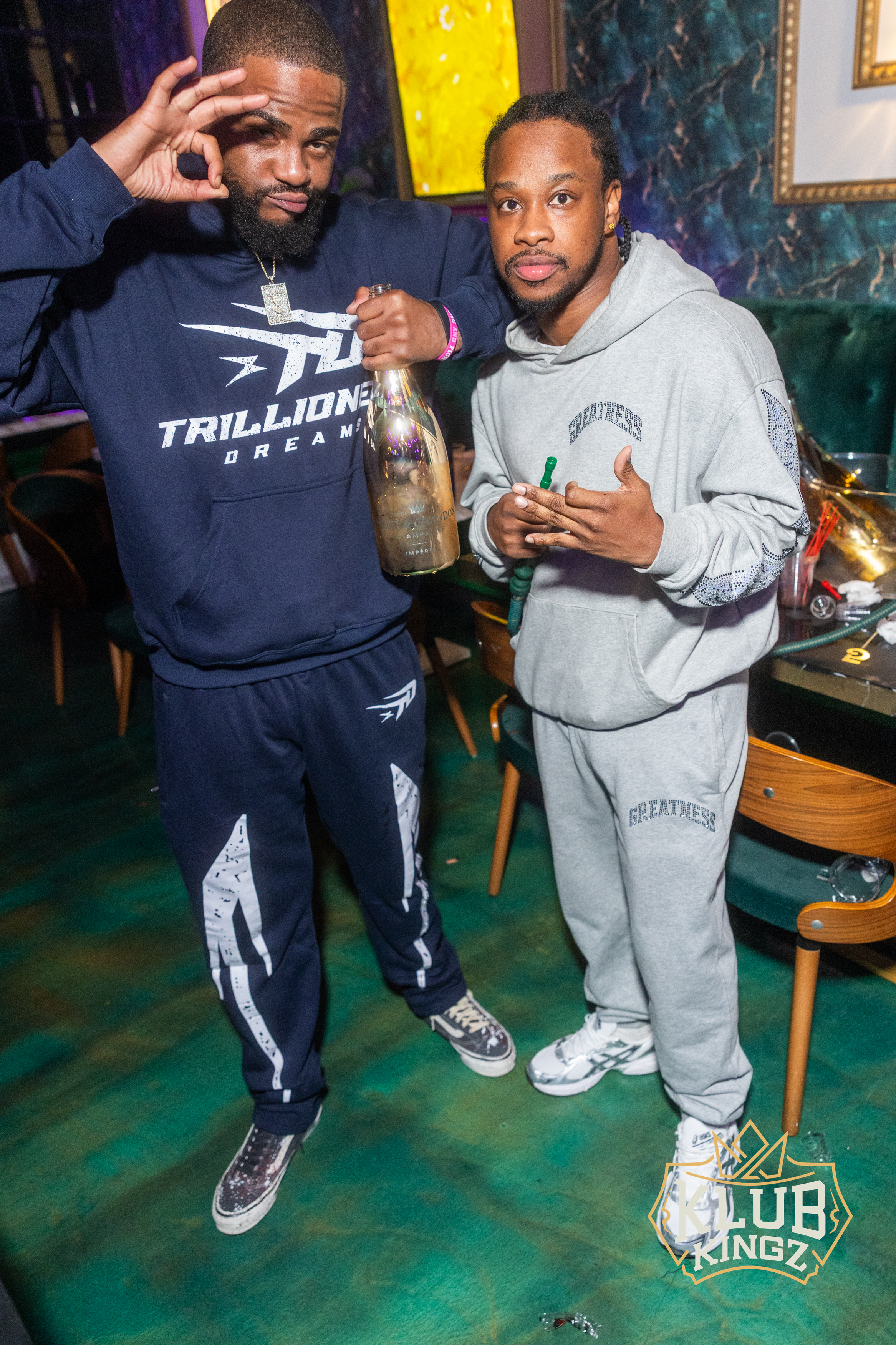 Two friends posing with champagne bottle at Klub Kingz nightclub event