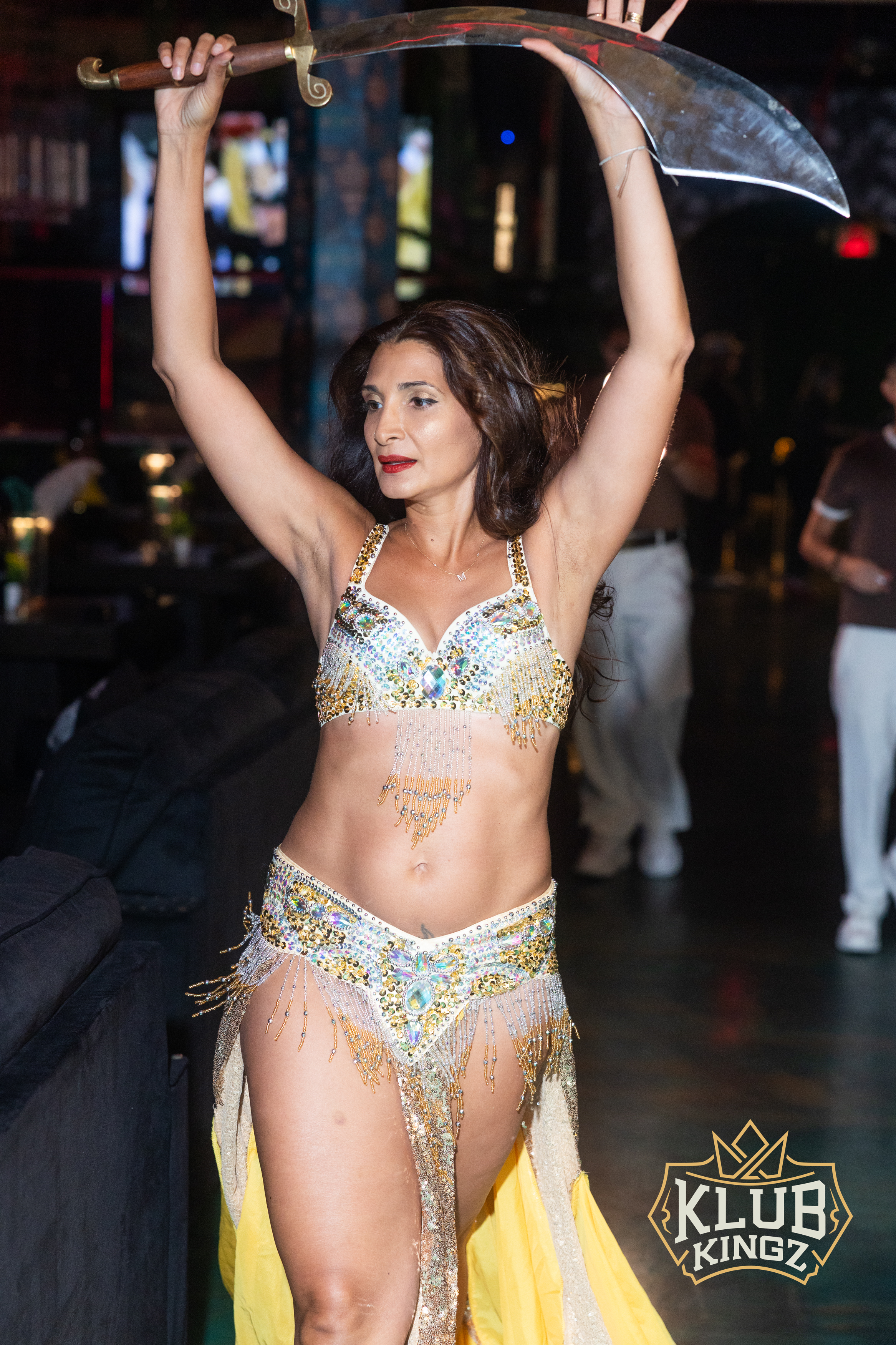 Belly dancer in sequined costume performs sword dance at Klub Kingz nightclub event