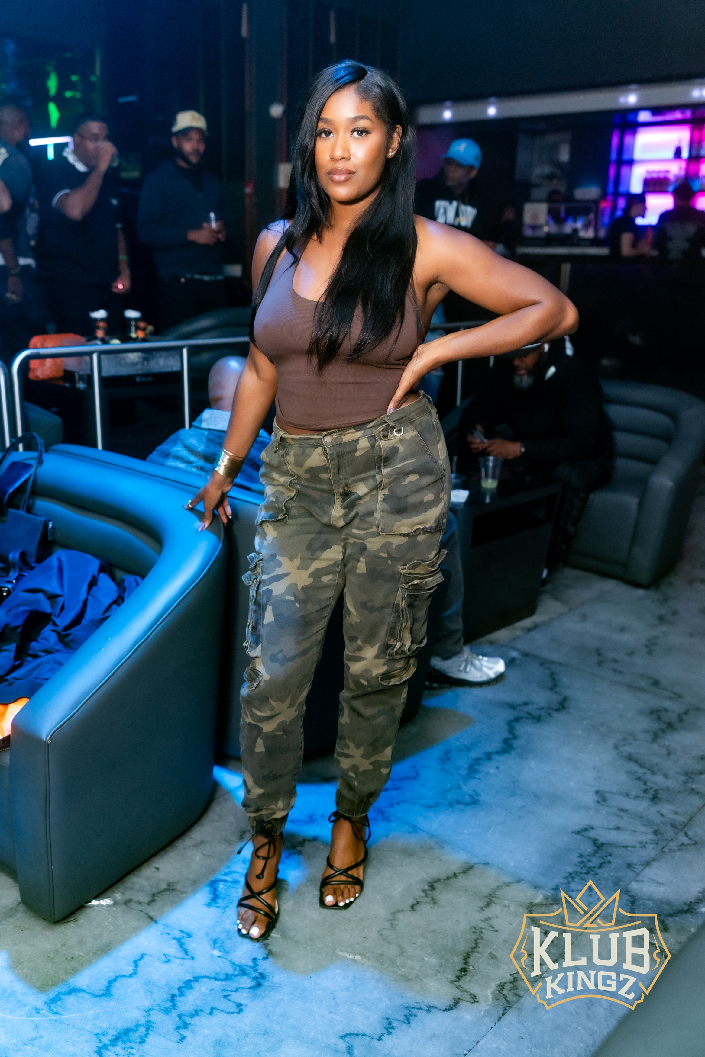Woman in camo pants and brown top posing at Klub Kingz nightclub event