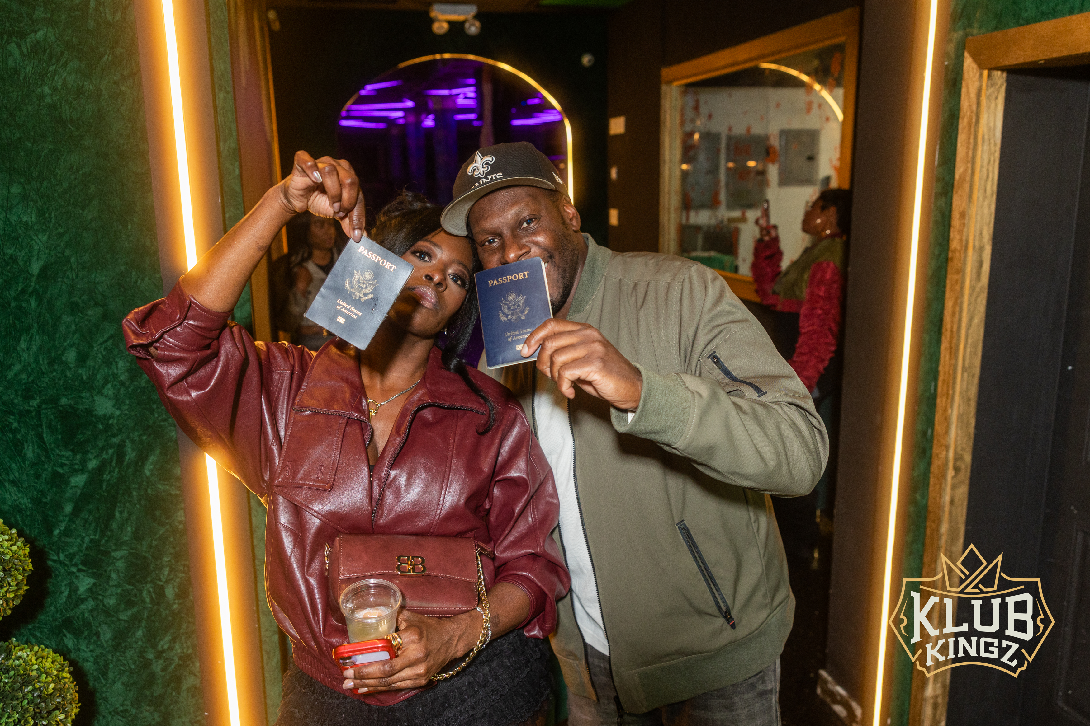 Couple holding up passports while posing at Klub Kingz nightclub entrance