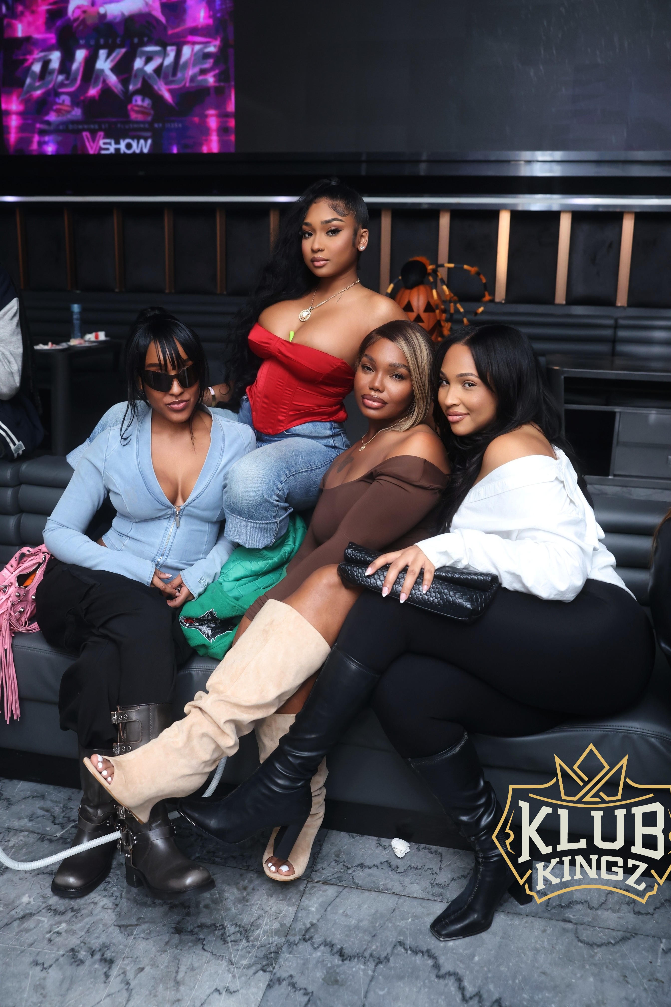 Four stylish women posing on a lounge couch at Klub Kingz nightclub event with DJ K Rue sign