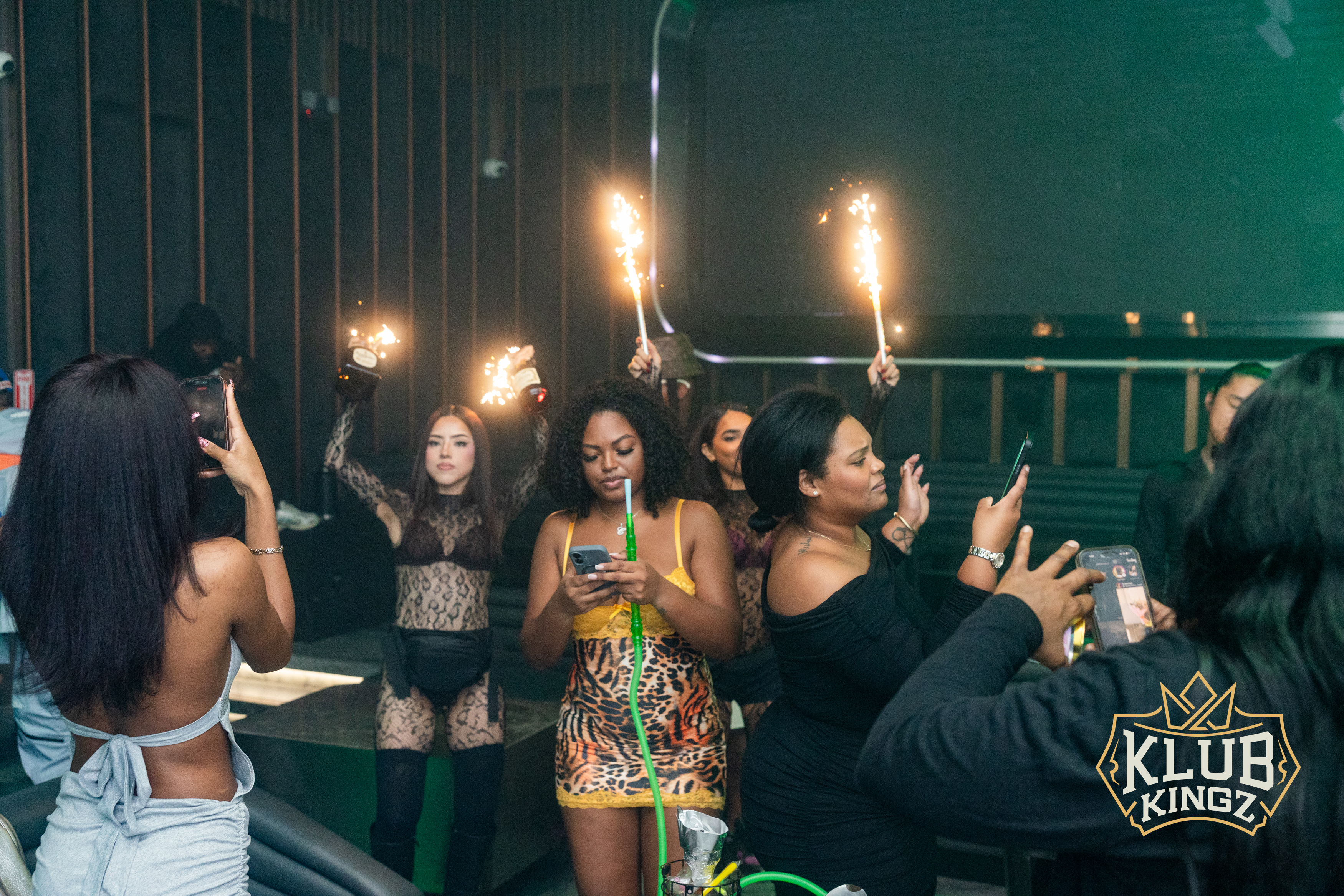 Bottle service with sparklers and hookah at Klub Kingz nightclub, guests capturing the moment on phones.