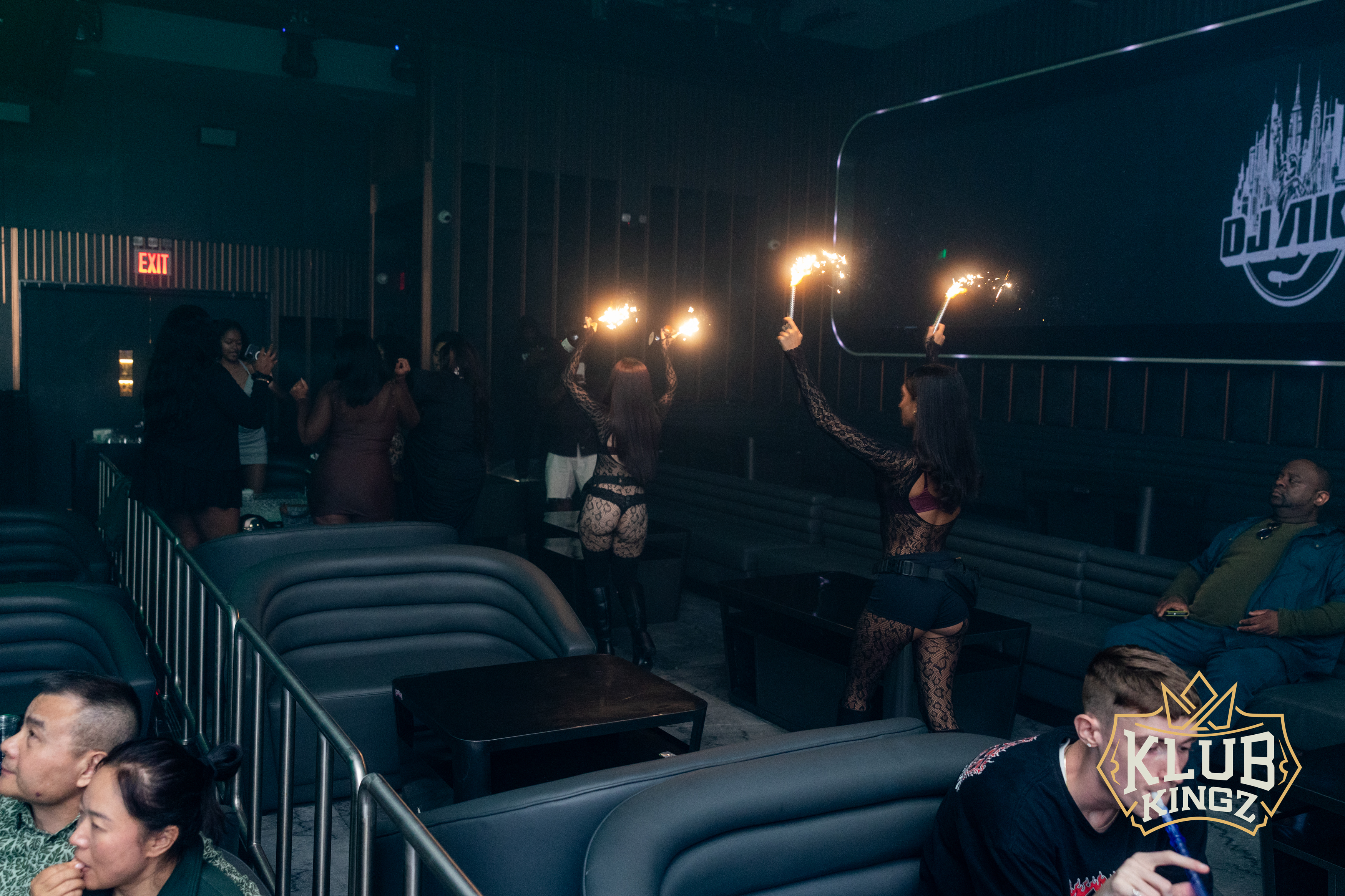 Dancers holding sparklers walk through VIP booth seating during a lively night at Klub Kingz nightclub.