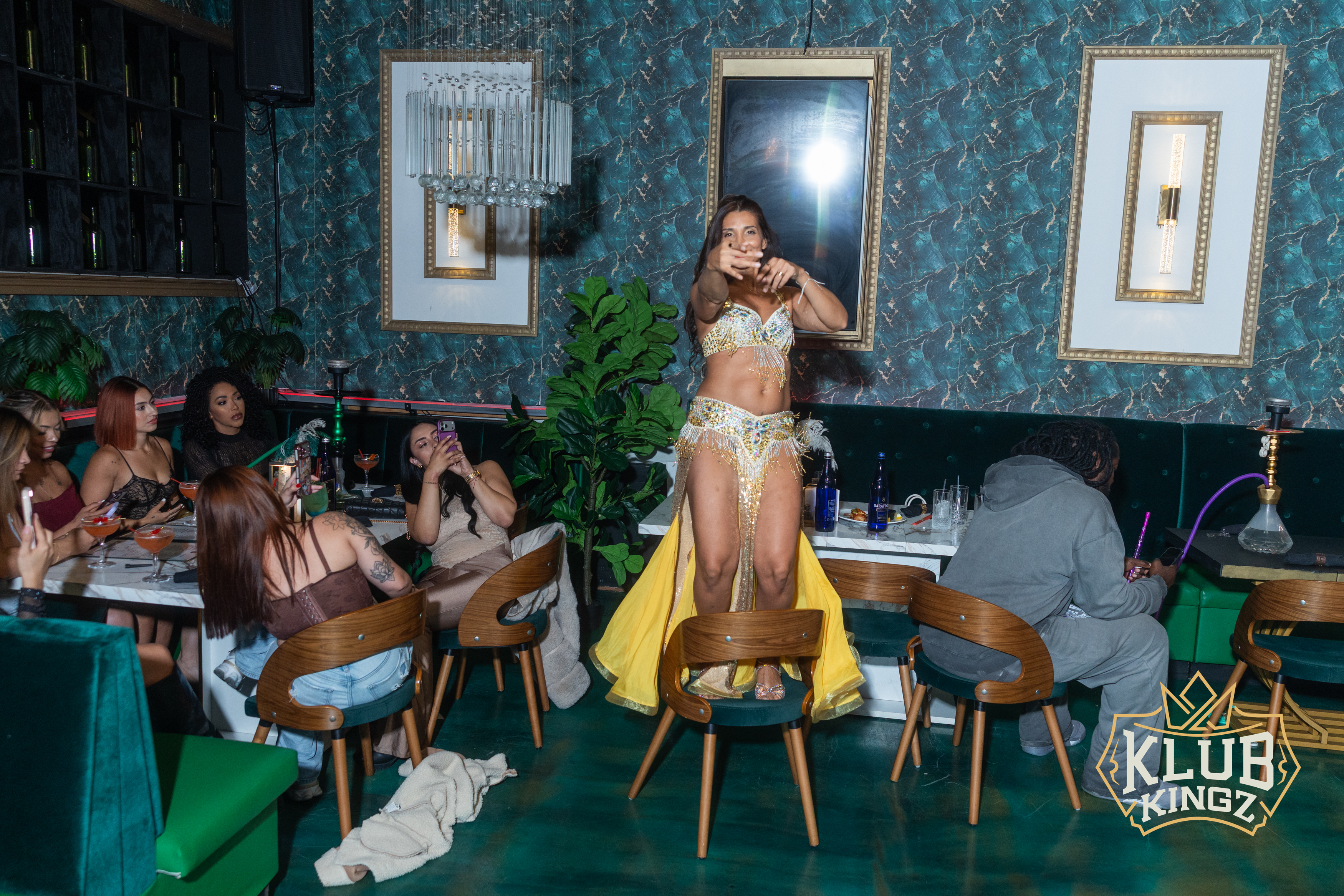 Belly dancer performing on a chair for guests at Klub Kingz lounge with hookah tables