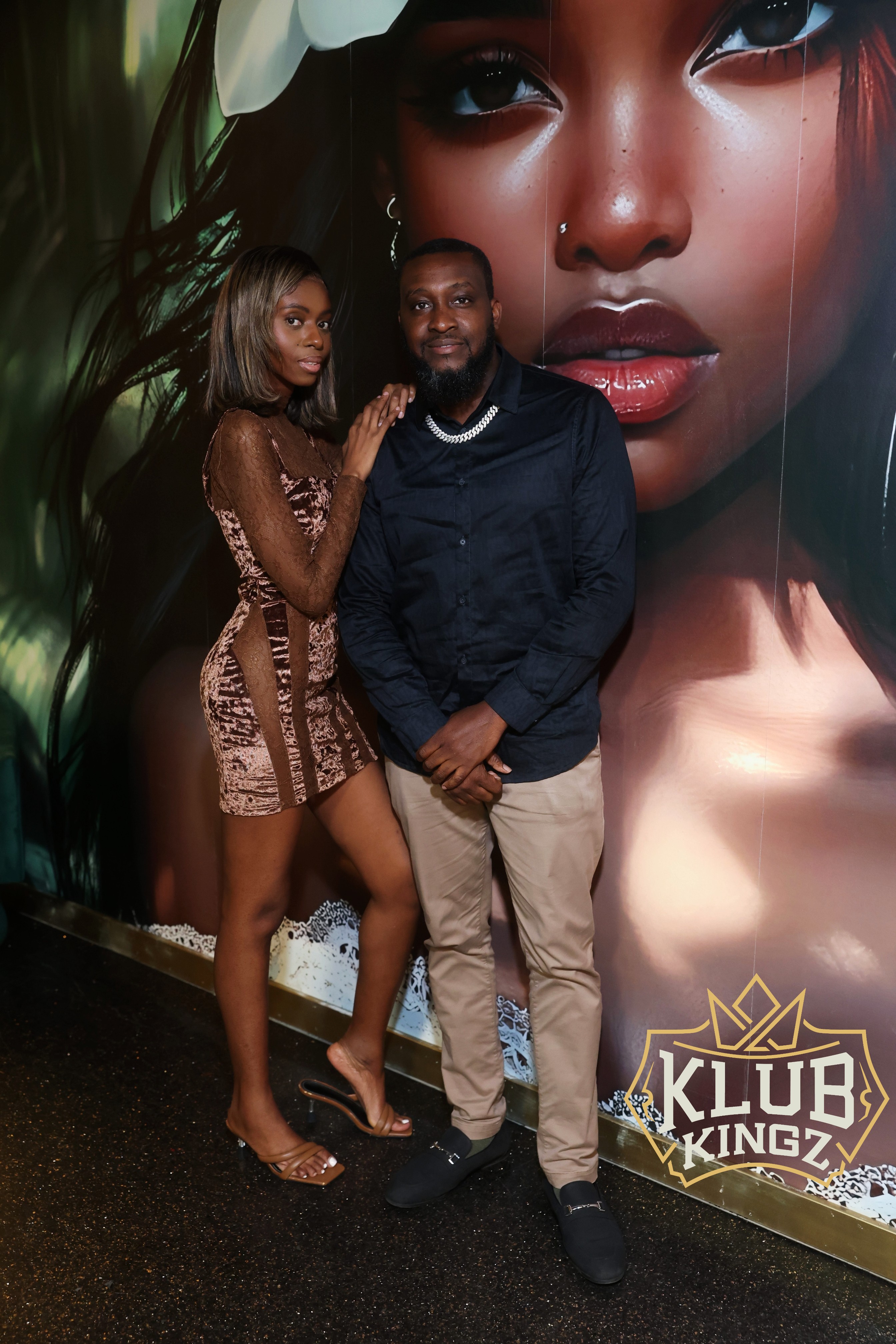 Couple posing together in front of mural wall at Klub Kingz nightclub event