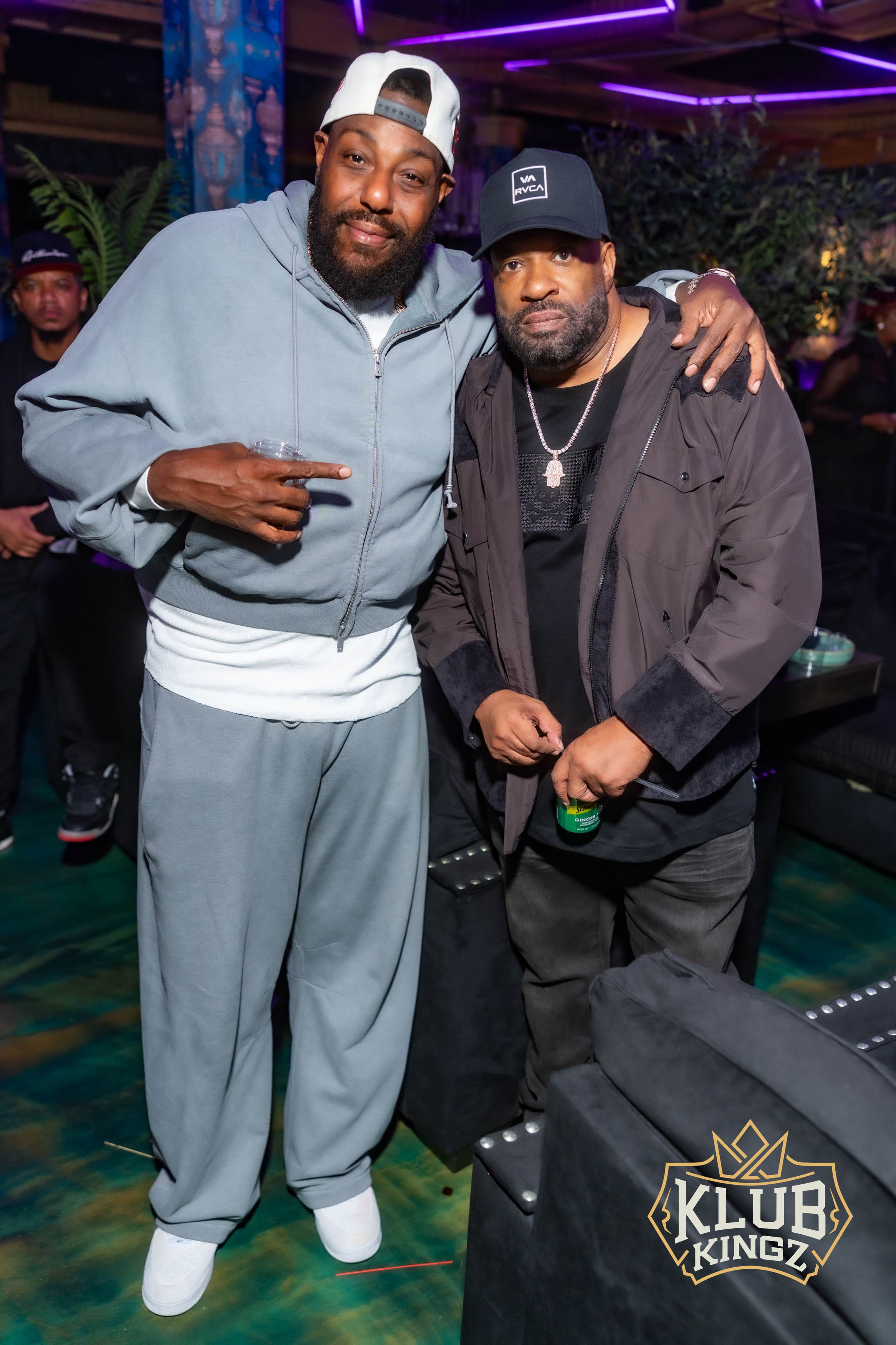 Two friends posing together at a Klub Kingz nightclub event with purple lighting
